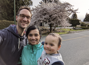 Dr. Joseph Westgeest with his wife and son in front of a blossoming cherry blossom tree. 